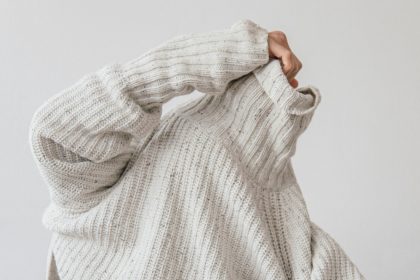 Image of someone pulling on a sweater - 10 ways to reduce your clothing waste and save money