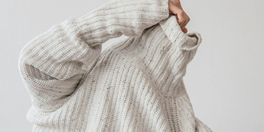 Image of someone pulling on a sweater - 10 ways to reduce your clothing waste and save money