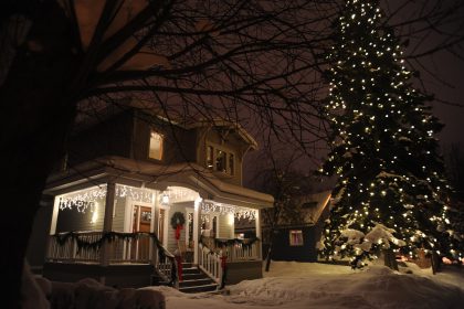 A picture of a house at night, decorated for christmas with lights and a wreath