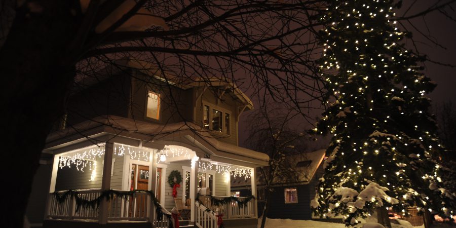 A picture of a house at night, decorated for christmas with lights and a wreath