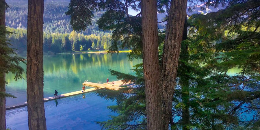 A picture of a lake in the summer time with people on the dock.