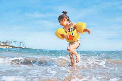 Small child playing on the beach splashing water