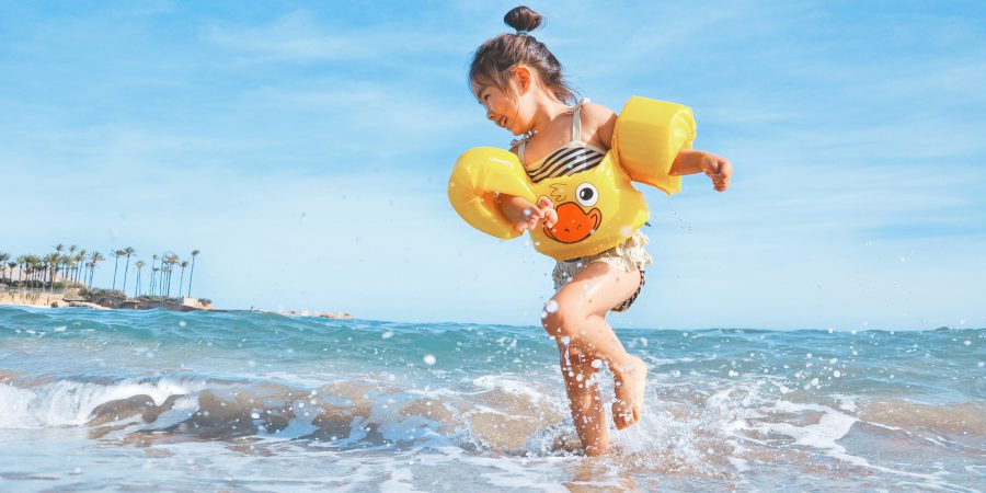 Small child playing on the beach splashing water