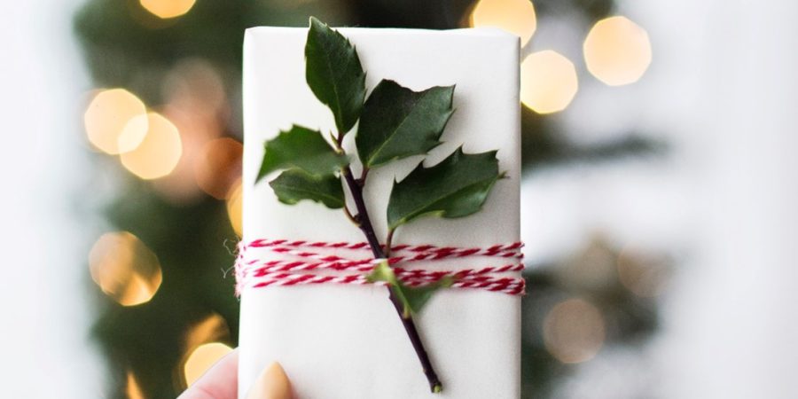 Someone holding a wrapped gift card in front of a christmas tree