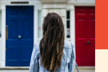 A woman with long brunette hair stands back on in front of a house. Image for a blog post on debt relief: credit counsellors vs debt repayment agents.